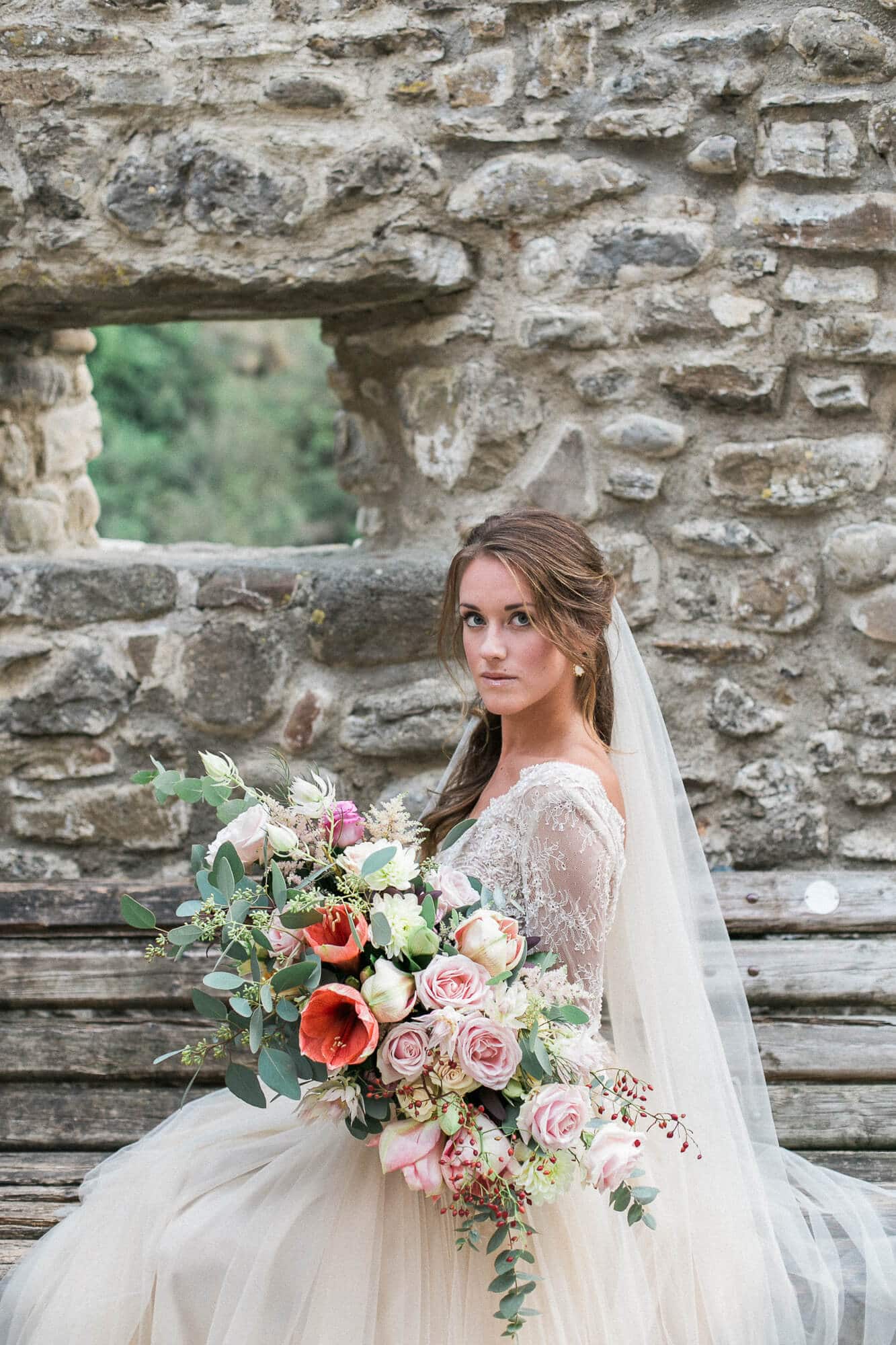A bride in a wedding dress and veil is holding a bouquet of flowers.