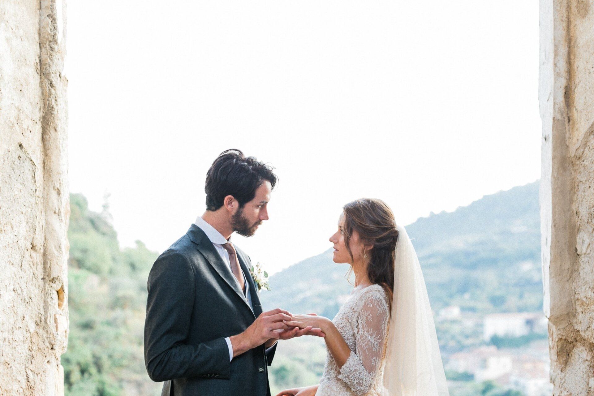 A bride and groom are getting married and the bride is putting the ring on the groom 's finger.