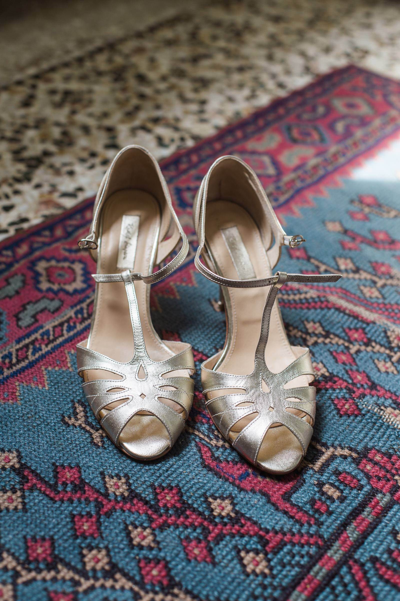 A pair of gold shoes sitting on top of a rug.