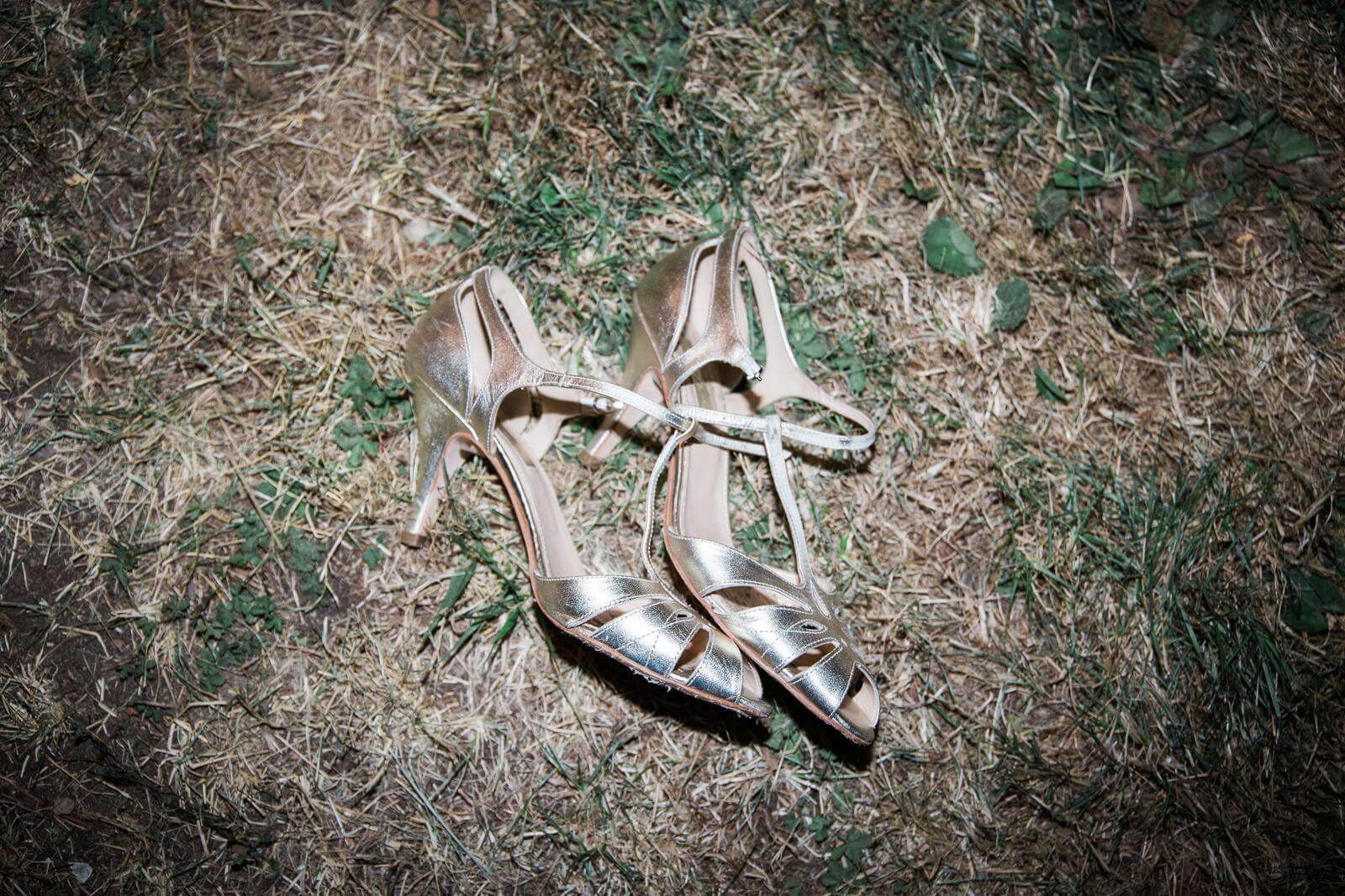 A pair of shoes are laying on the ground in the grass.