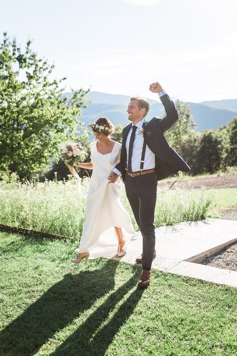 A bride and groom are walking down a path holding hands.