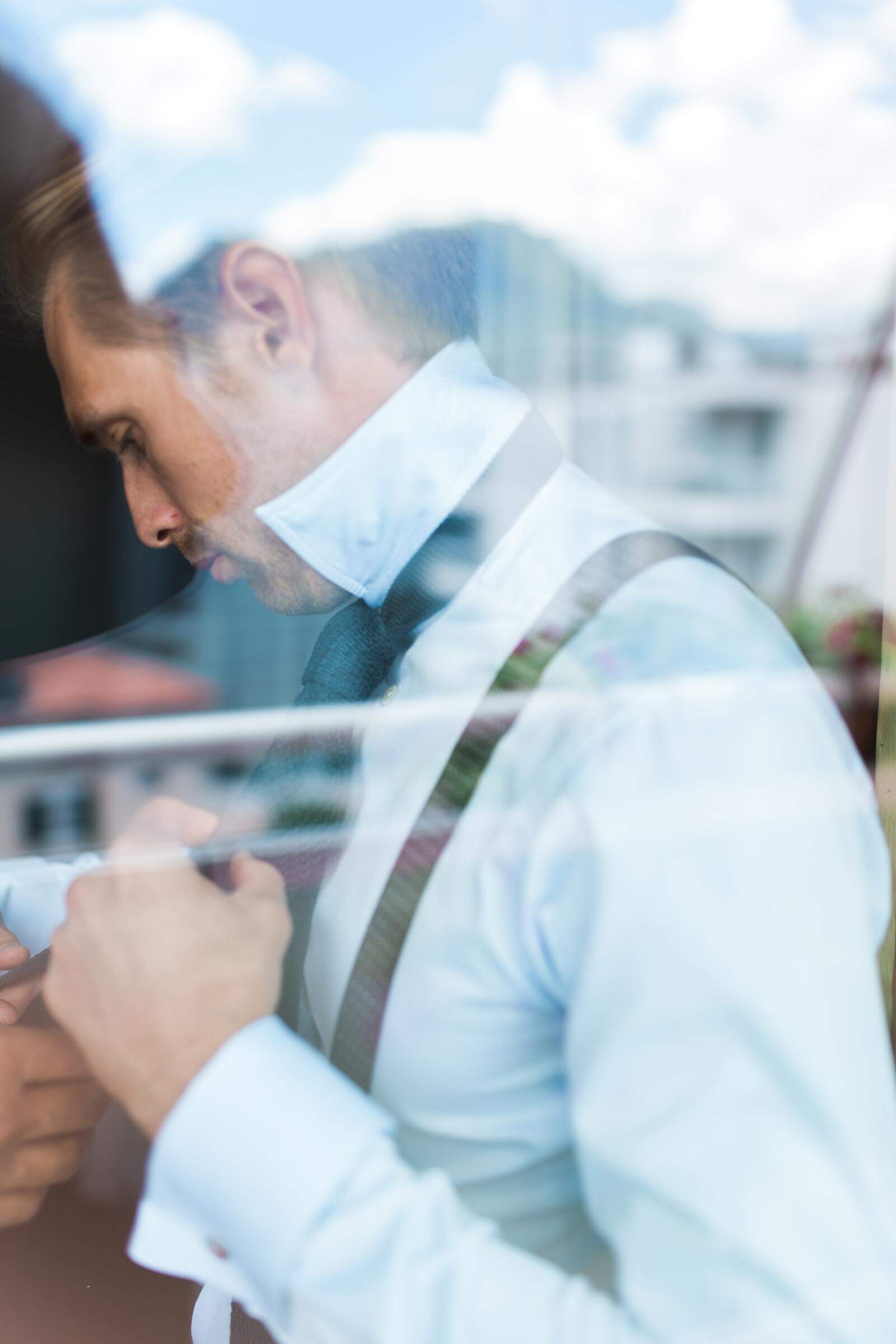 A man in a bow tie and suspenders is looking out of a window.