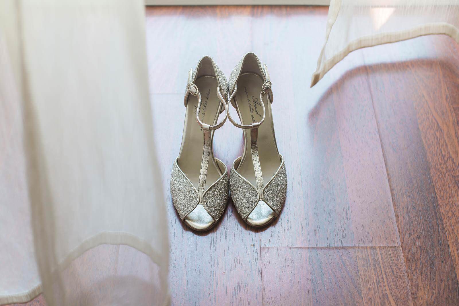 A pair of wedding shoes are sitting on a wooden floor.