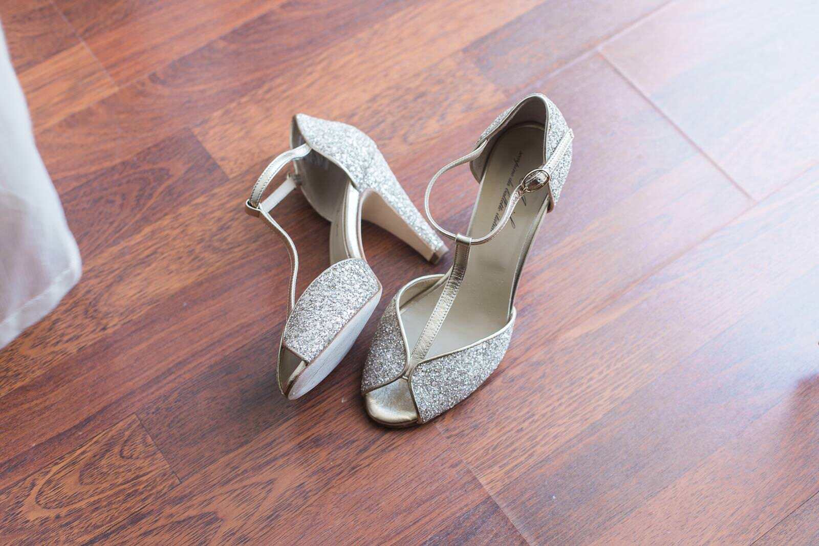 A pair of wedding shoes are sitting on a wooden floor.