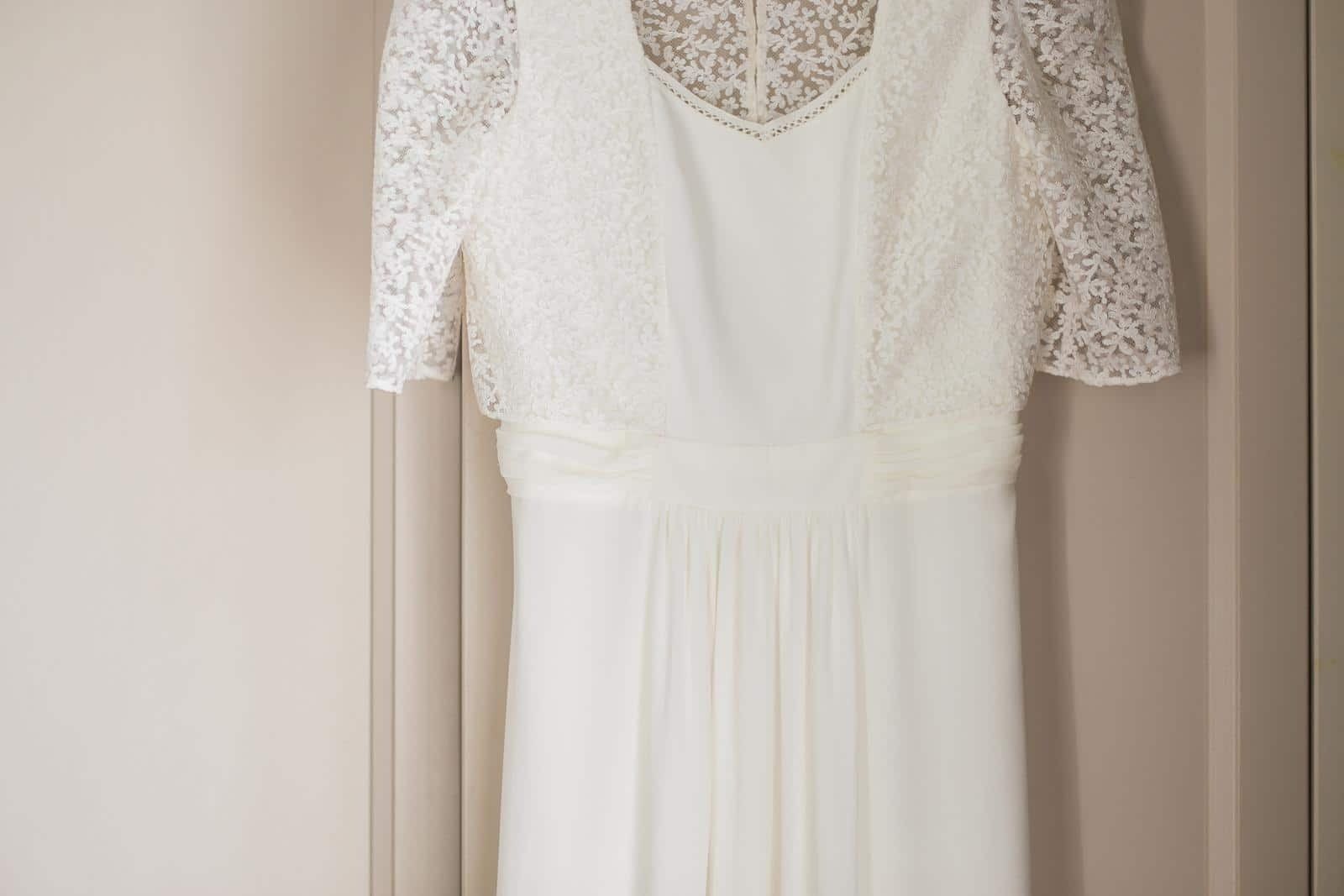 A white wedding dress is hanging on a door.