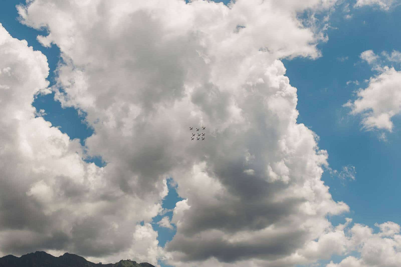 A group of planes are flying through a cloudy blue sky.