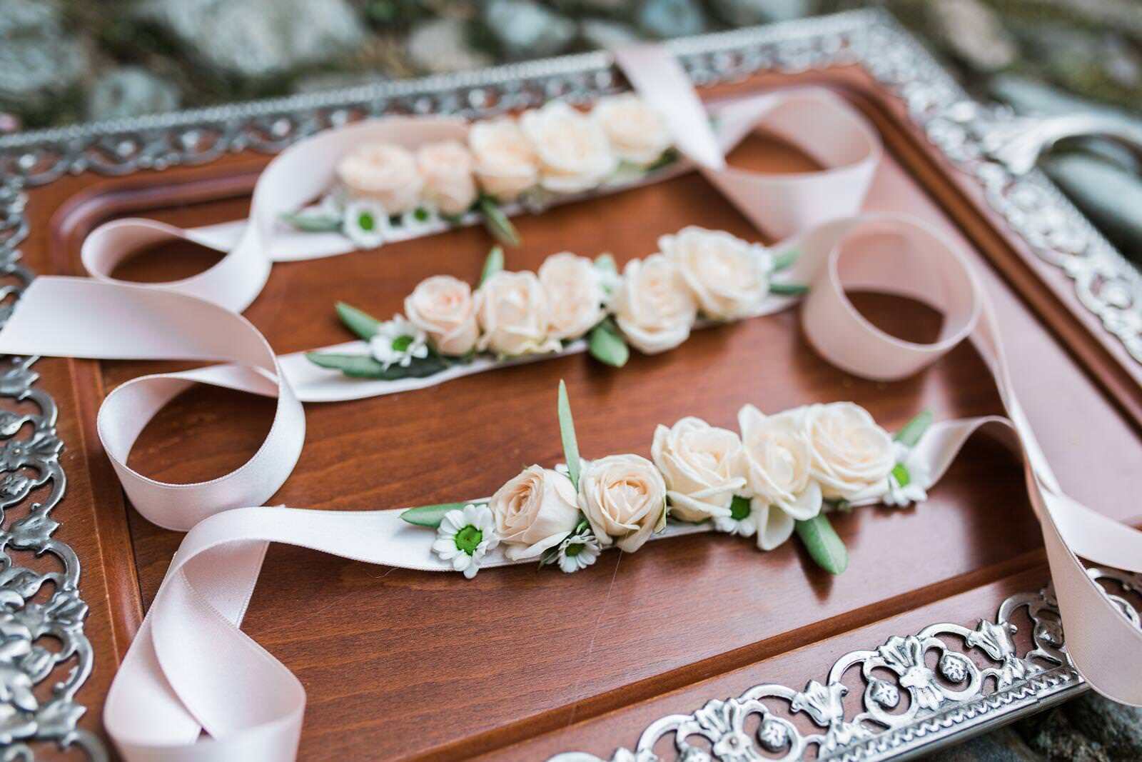 A wooden tray with flowers and ribbons on it.