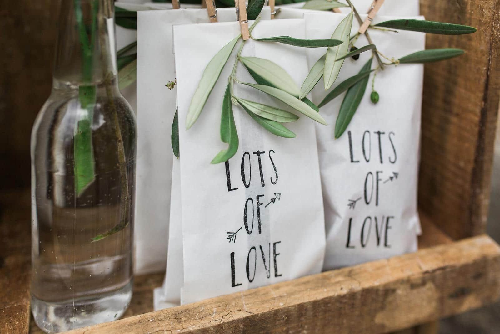 A wooden box filled with lots of love bags and a bottle of water.