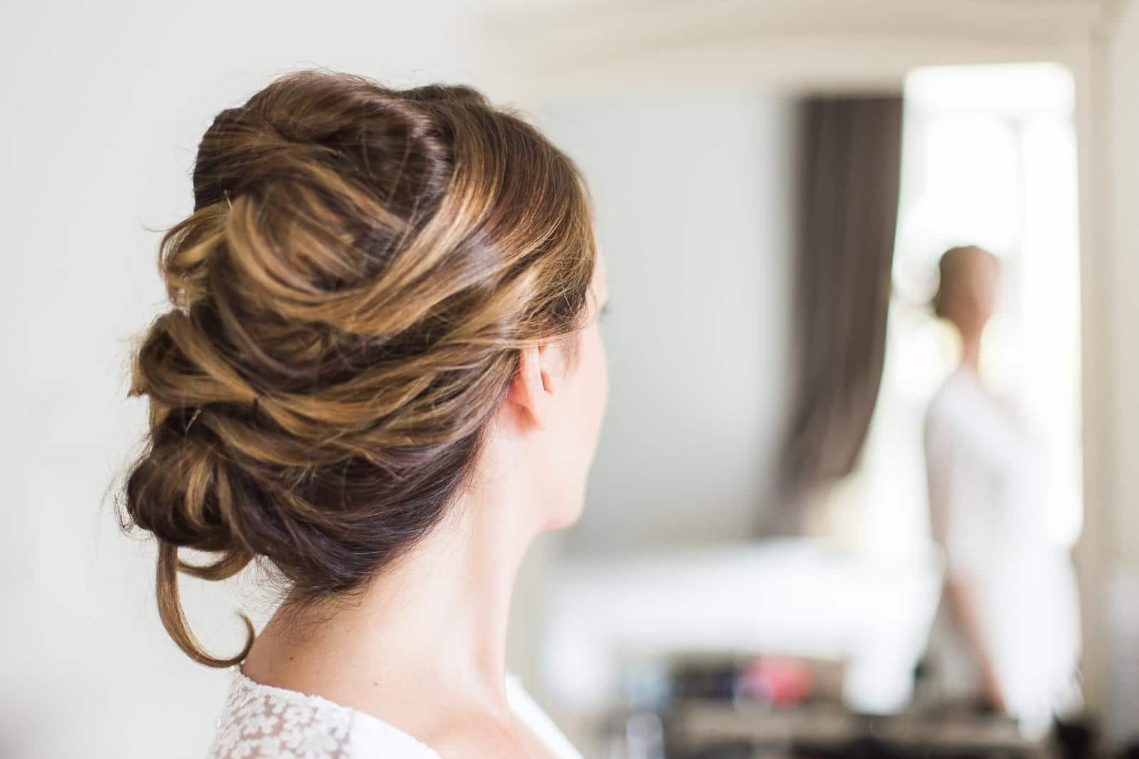 A woman is getting her hair done in front of a mirror.