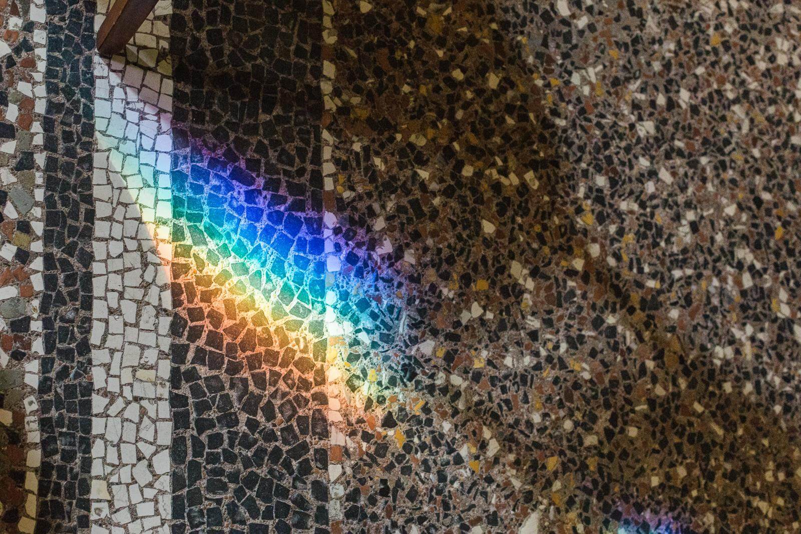 A rainbow is reflected in a mosaic wall.