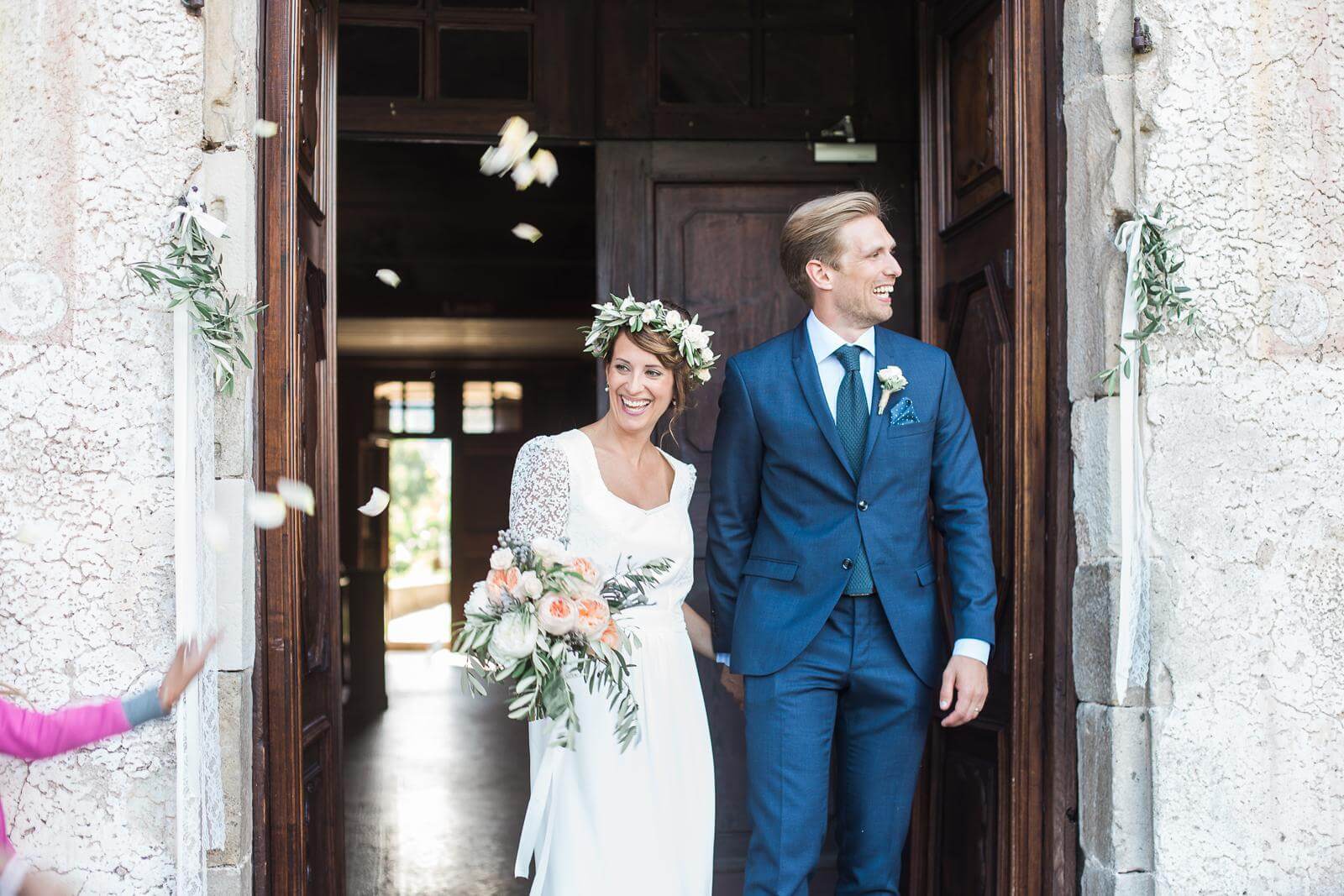 A bride and groom are walking out of a church holding hands.