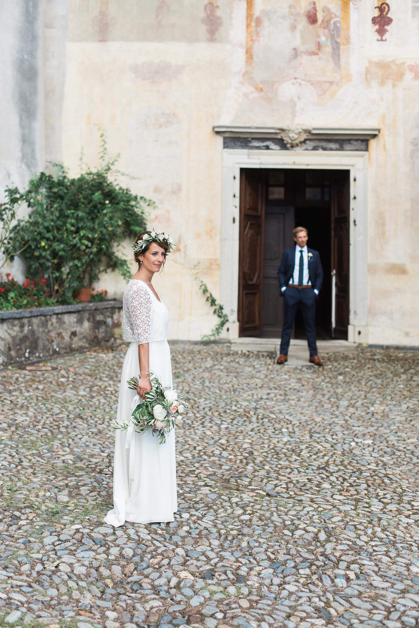 A bride and groom are posing for a picture in front of a church.