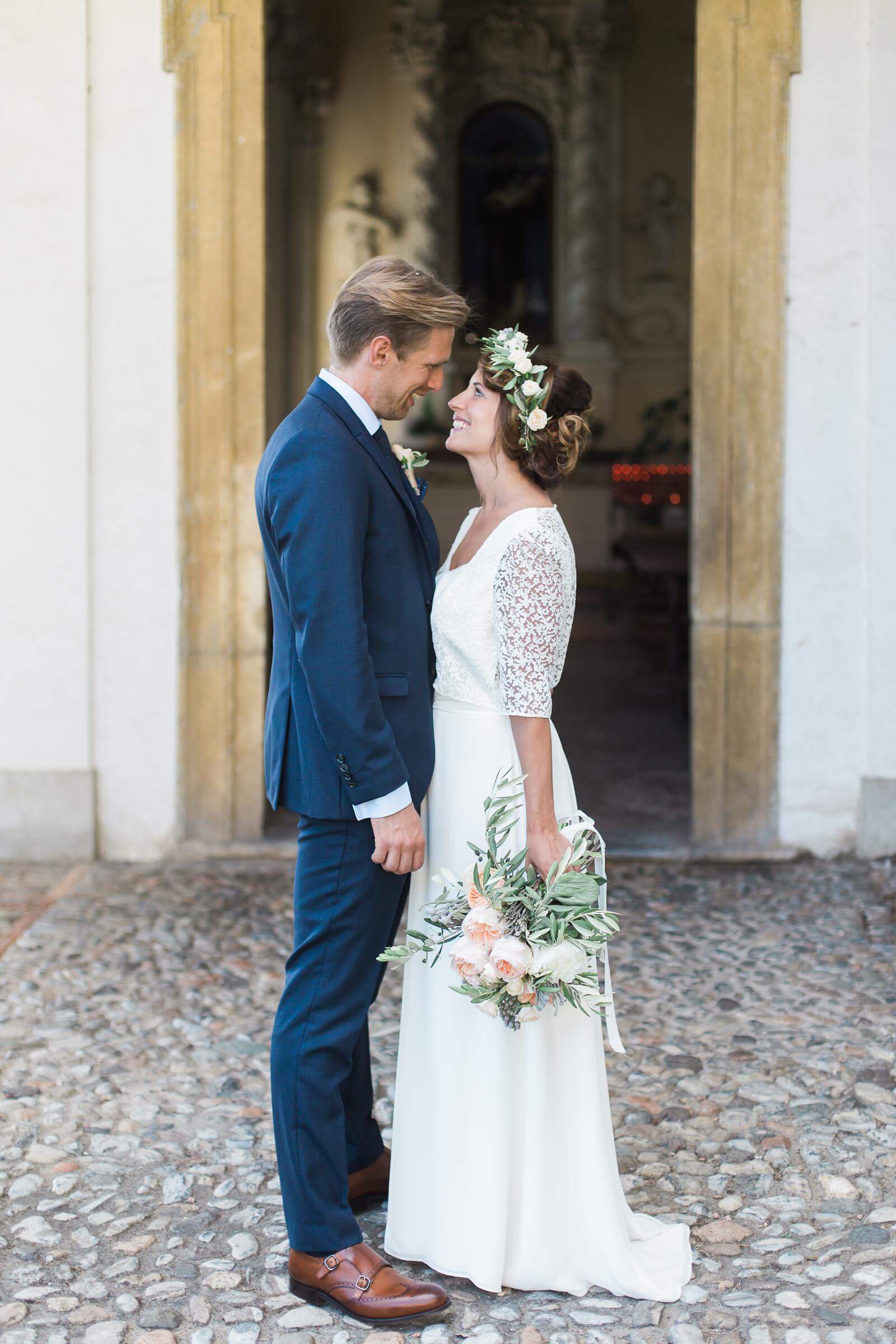 A bride and groom are standing next to each other in front of a building.