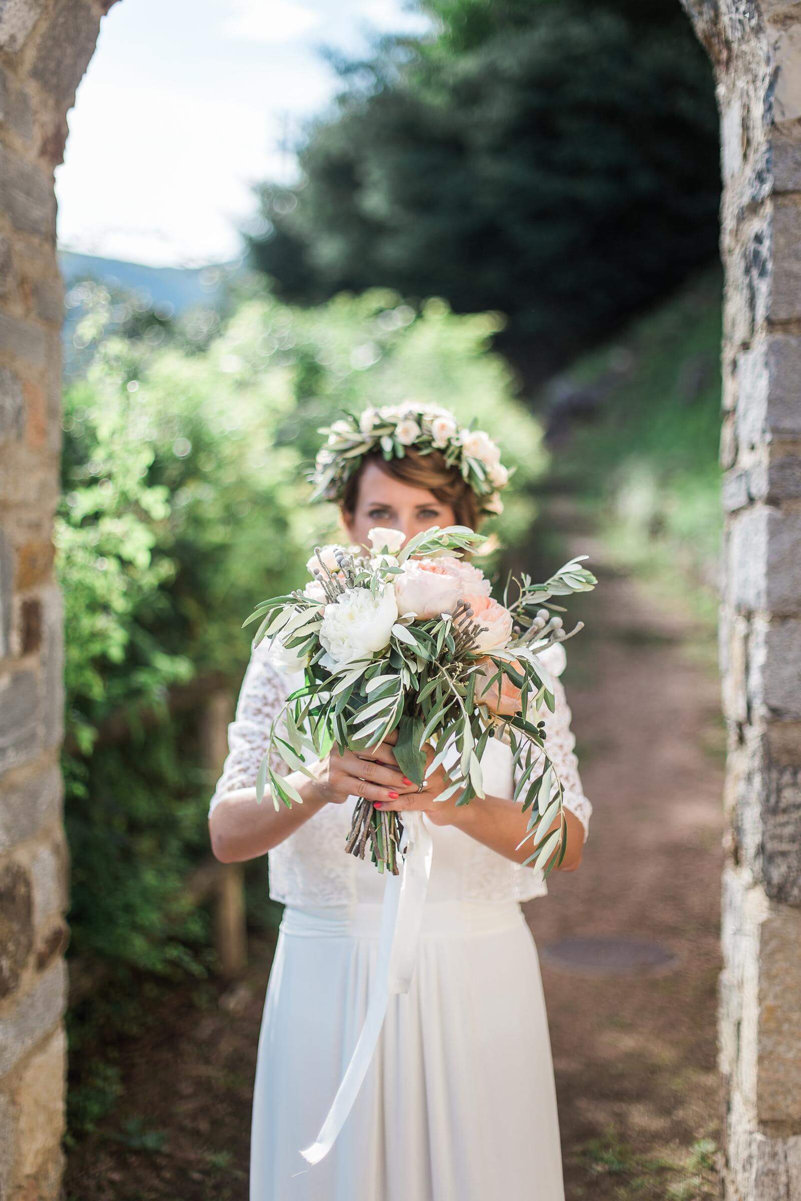 The bride is wearing a flower crown and holding a bouquet of flowers.