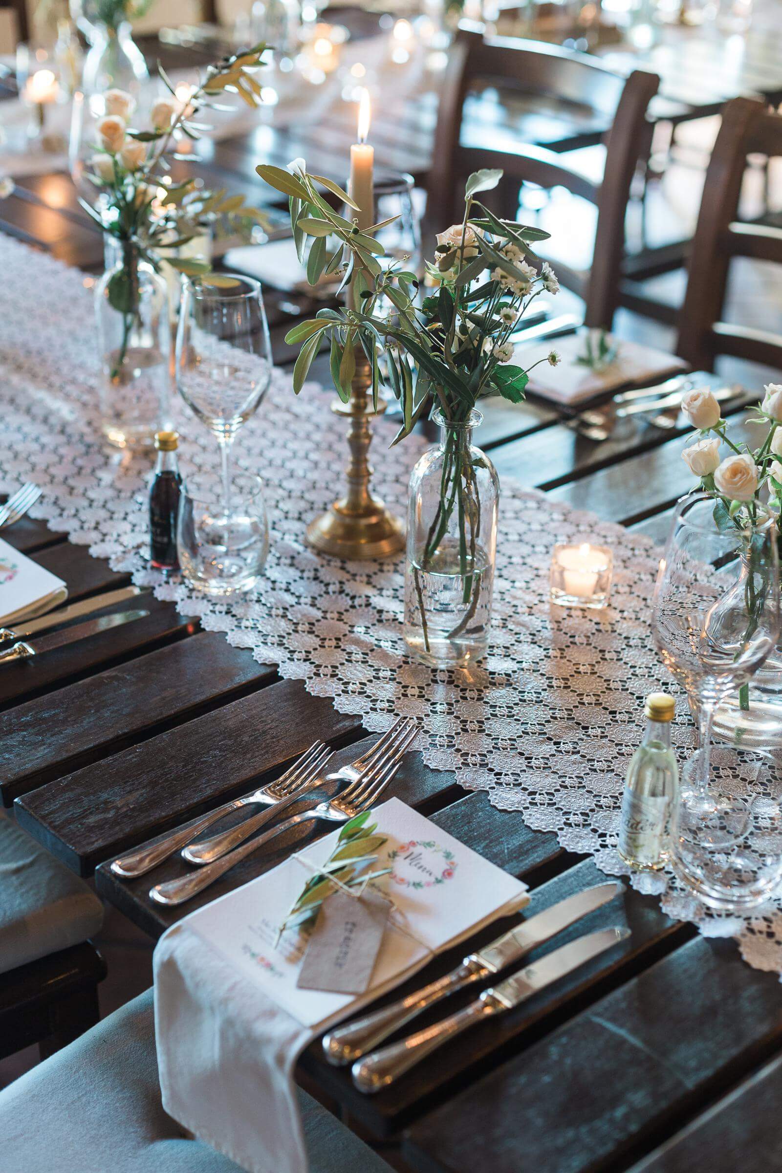 A table set for a wedding reception with flowers and candles on it.