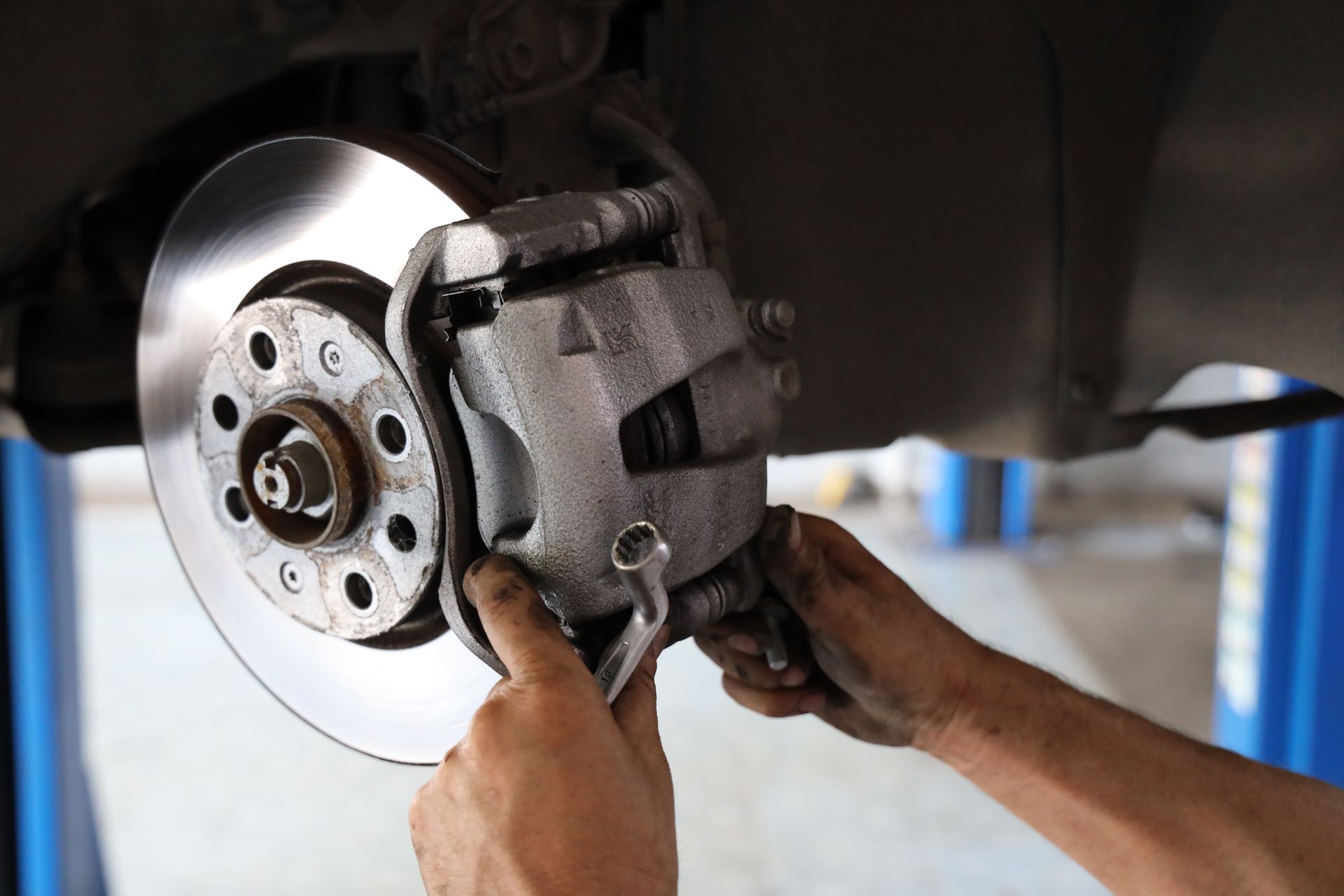 A person is fixing a brake caliper on a car.