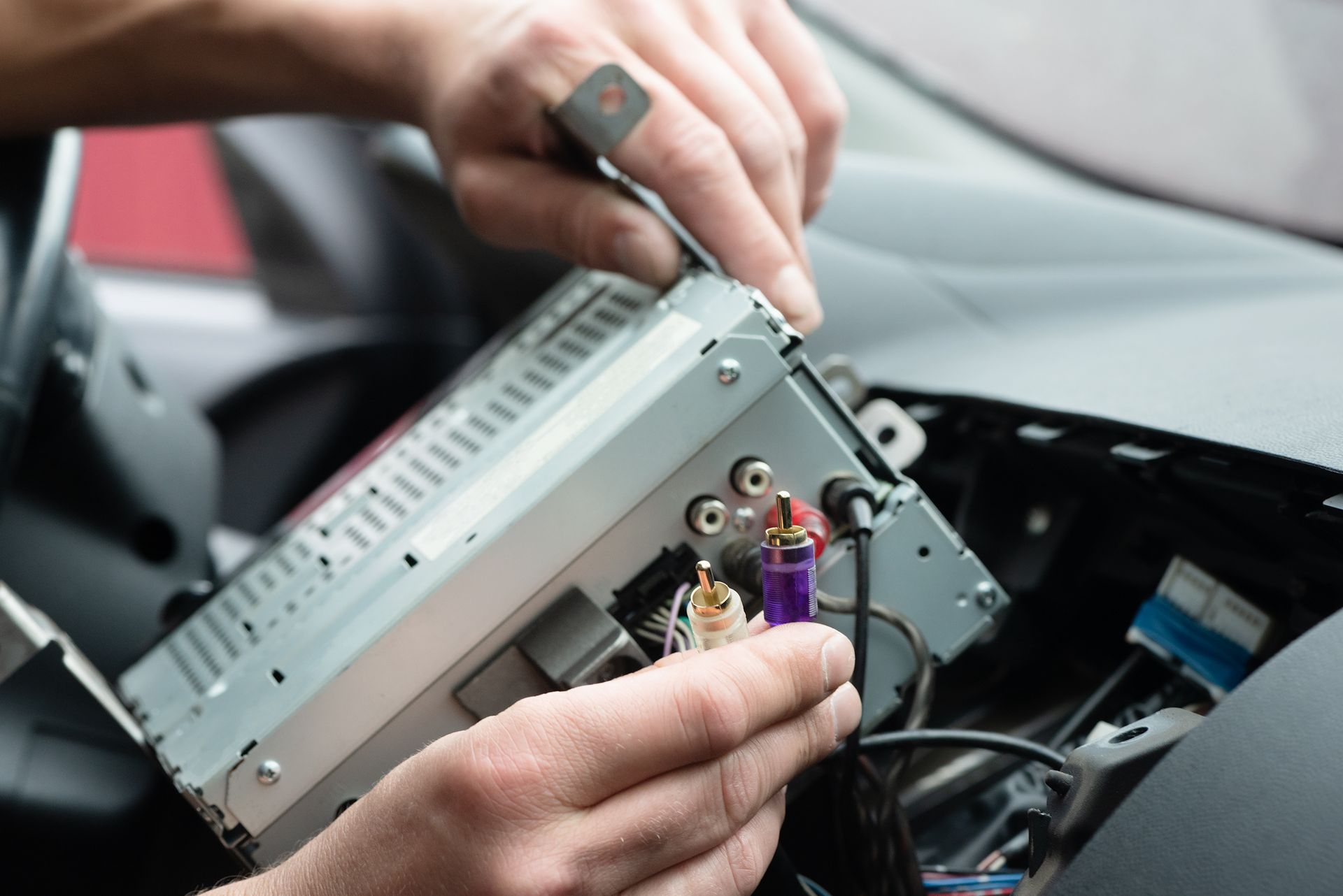 A person is installing a radio in a car with a screwdriver.