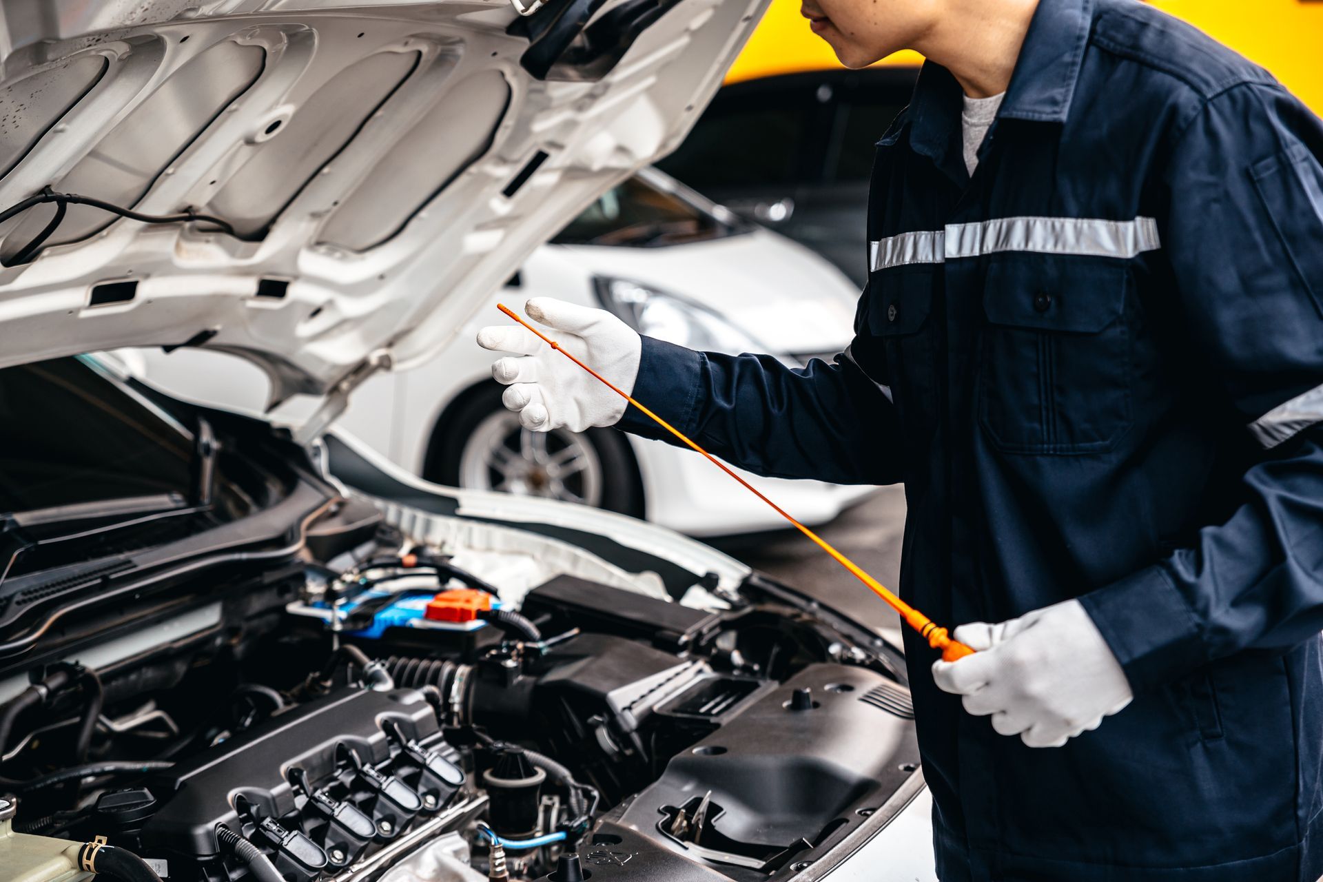 A man is checking the oil in a car with the hood open.