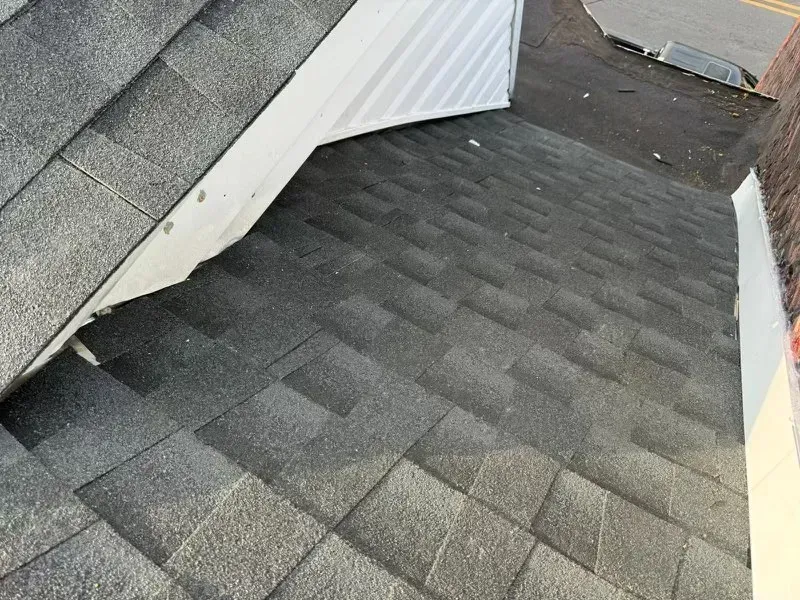 Rooftop section with dark gray shingles and a white dormer wall.