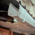 Icy white gutter dripping water under a roof eave indoors