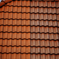Red clay roof tiles against a blue sky, with a small section of chimney on the left.