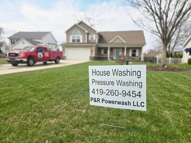 Lawn sign advertising house washing and pressure washing services in a suburban yard, with a red truck nearby