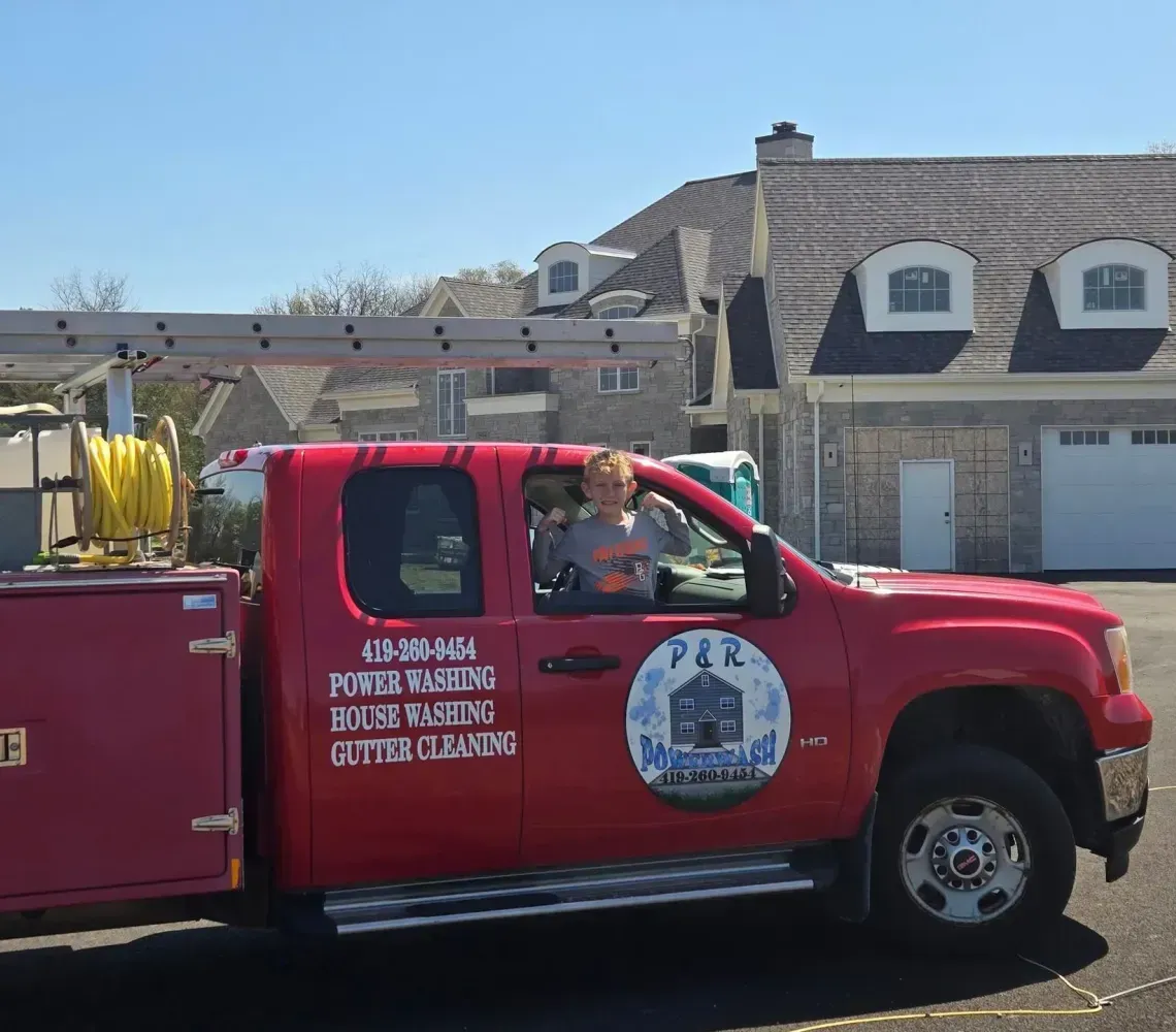 Red fire truck parked on a residential street with a firefighter in the cab and ladder equipment on top