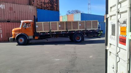 Personas cargando cajas y equipos en un camión en un área de estacionamiento al aire libre soleada.