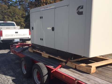 A chevrolet truck is towing a generator on a trailer.