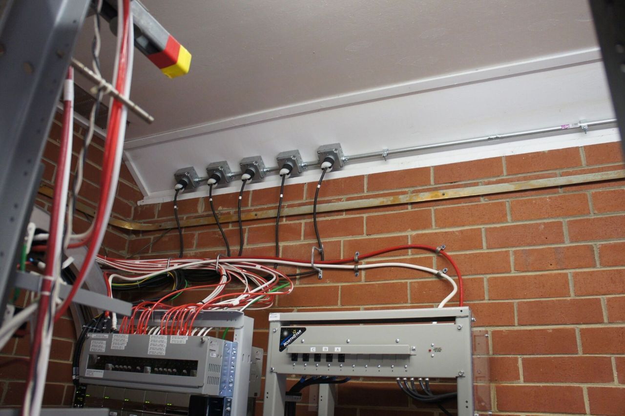 A brick wall with a bunch of wires hanging from it