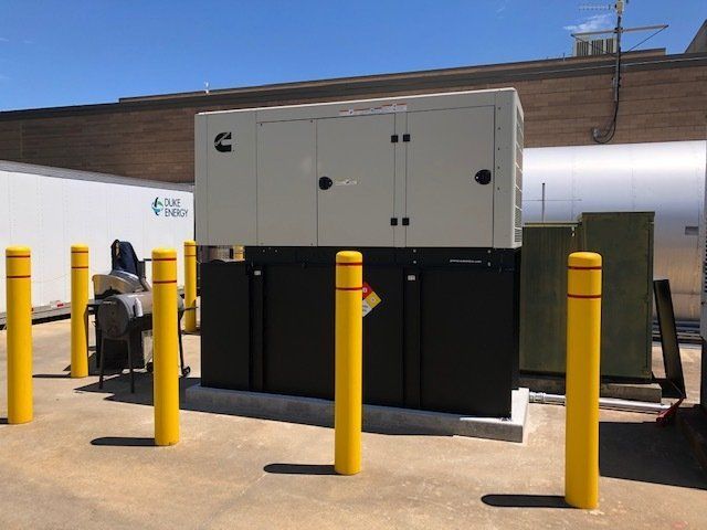 A large cummins generator is surrounded by yellow poles