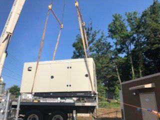 A crane is lifting a generator into a building.