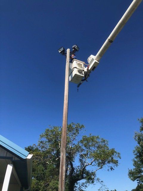 A man in a bucket is working on a light pole.