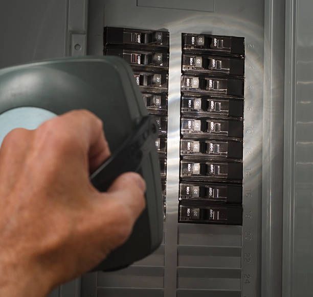 A person is holding a light in front of a electrical panel