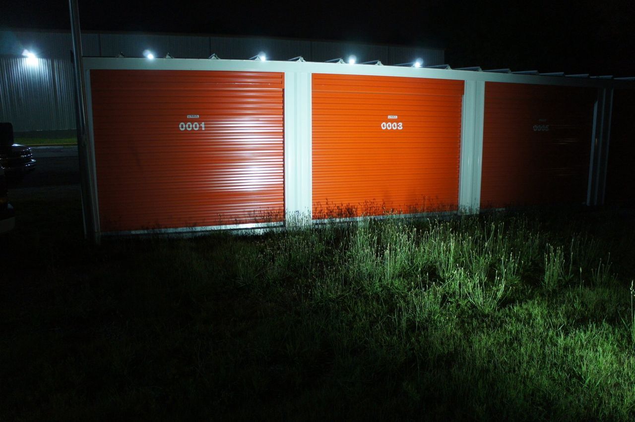 A row of storage units are lit up at night.