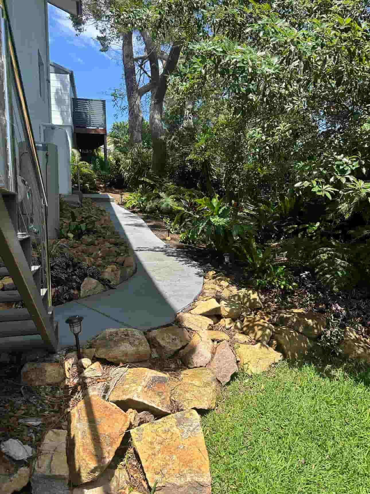 A Stone Walkway Leading To A House Surrounded By Trees And Grass — Gibbo’s Lawns & Property Maintenance In Salamander Bay, NSW