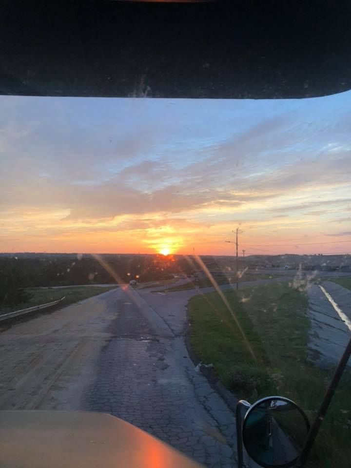A sunset is visible through the windshield of a truck.