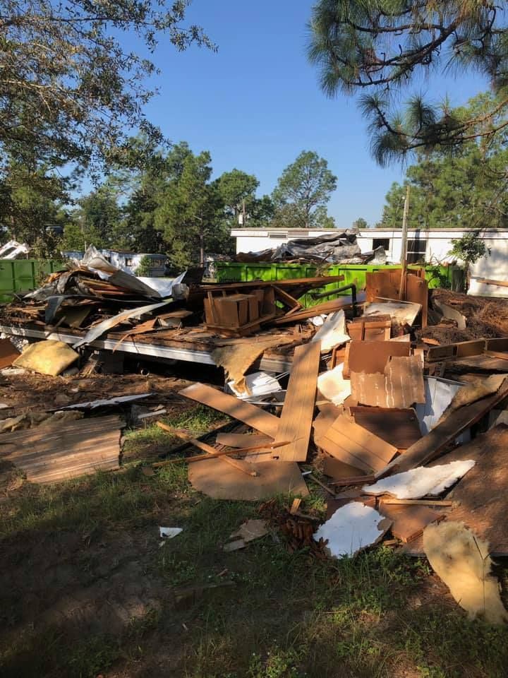 A pile of cardboard is sitting in the grass in front of a mobile home.