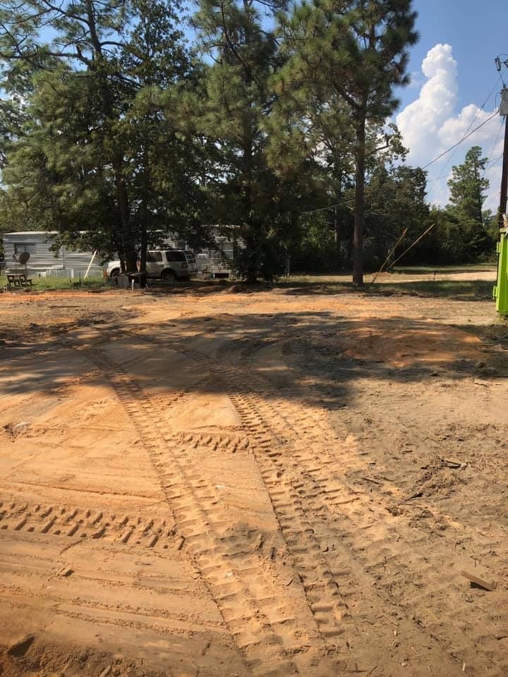 A dirt road with a trailer parked in the background and trees in the background.
