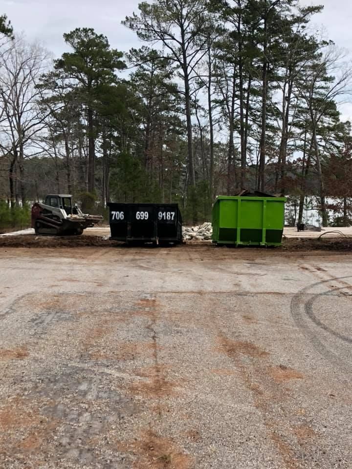 A green dumpster is sitting next to a black dumpster in a parking lot.