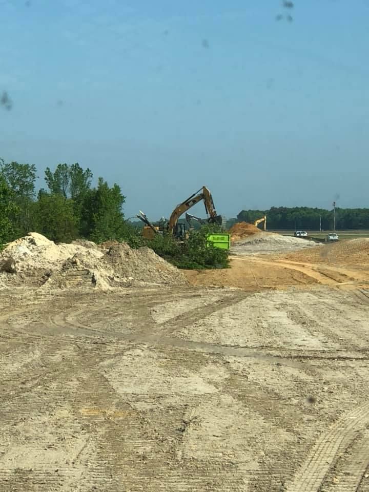 A large excavator is working on a dirt road