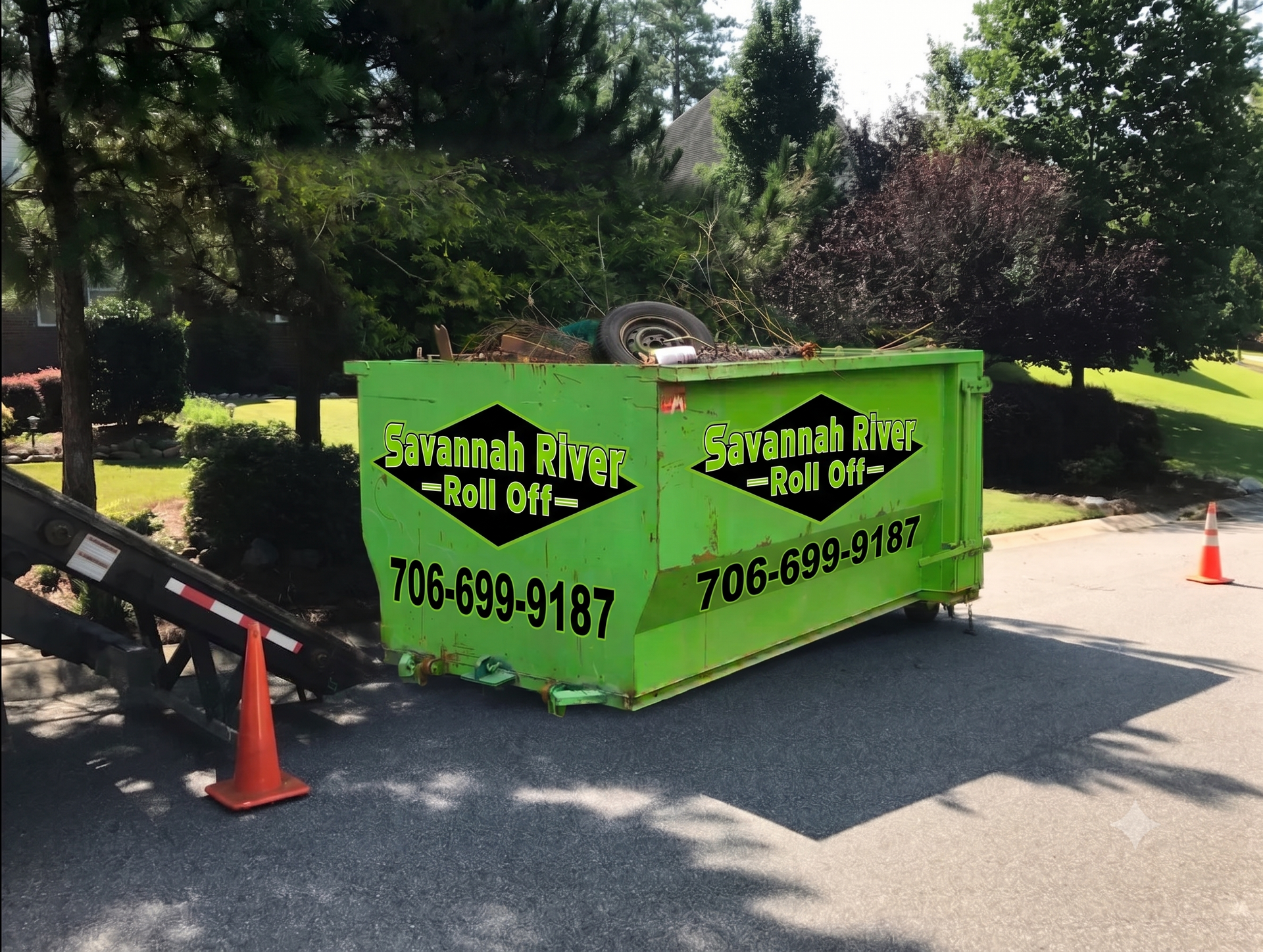 A green dumpster is parked on the side of the road