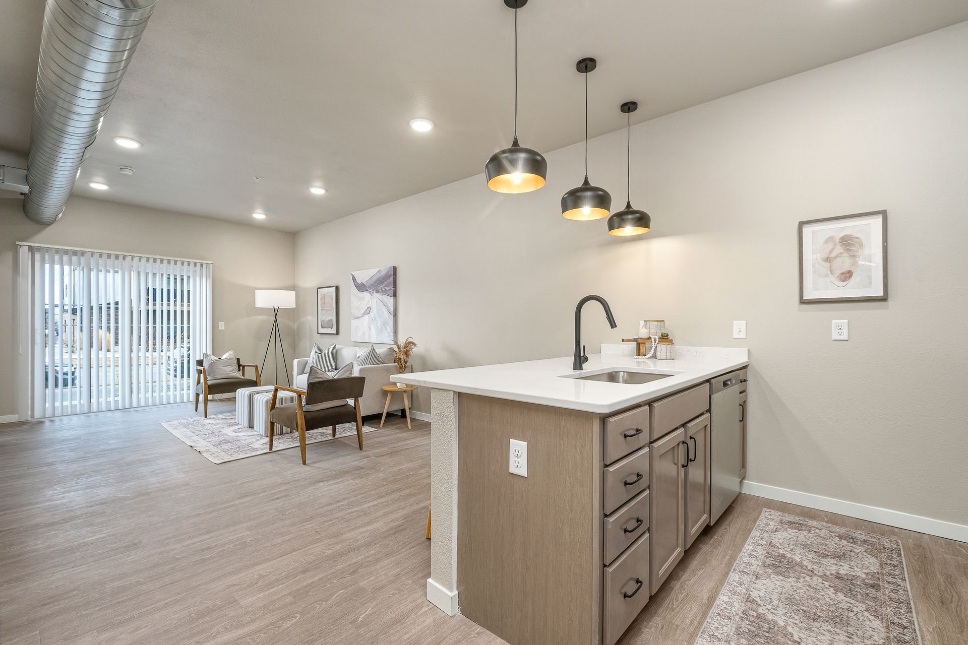 A kitchen with a large island and a sink in a living room.