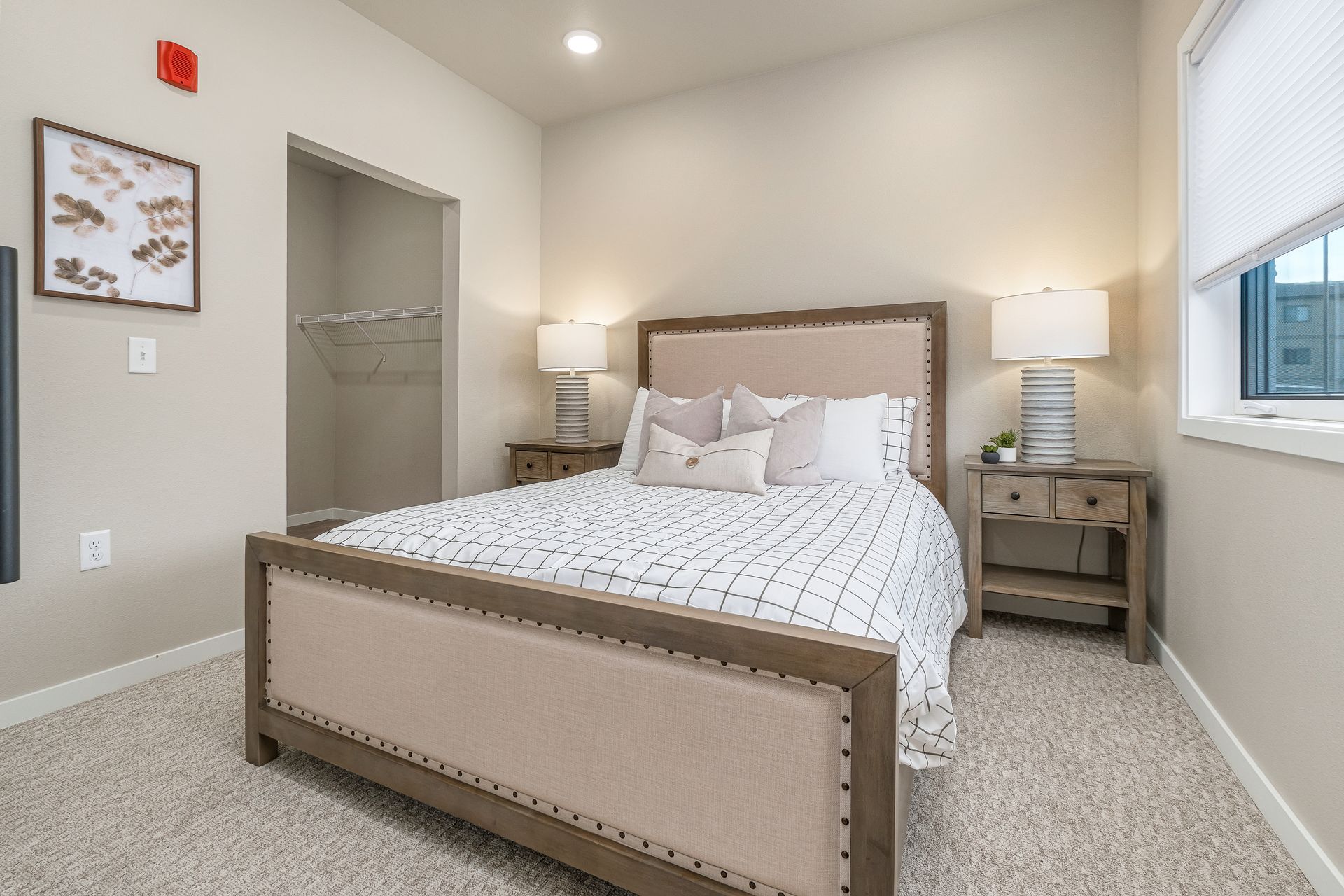 A bedroom with a bed , nightstands , lamps and a window.