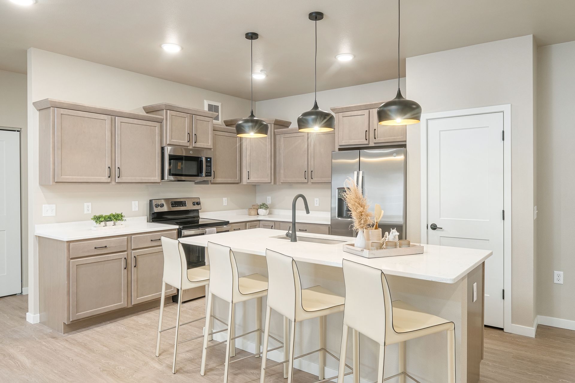 A kitchen with white cabinets , stainless steel appliances , and a large island.