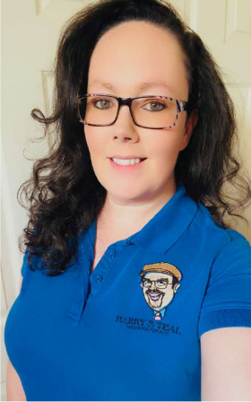 Smiling person in glasses wearing a blue polo shirt with an embroidered logo.