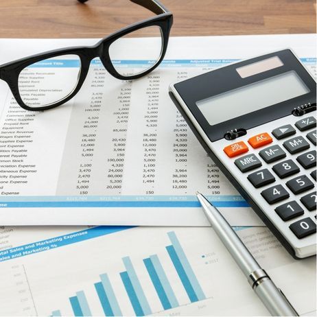 Financial documents with glasses, calculator, and pen on a wooden surface.