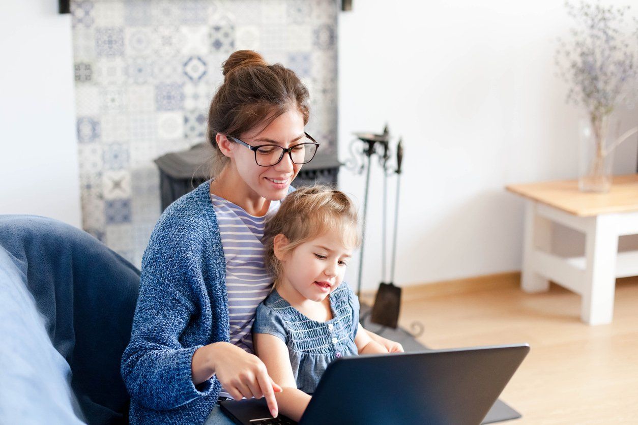 Mother and Daughter Sitting in Chair With Laptop Computer