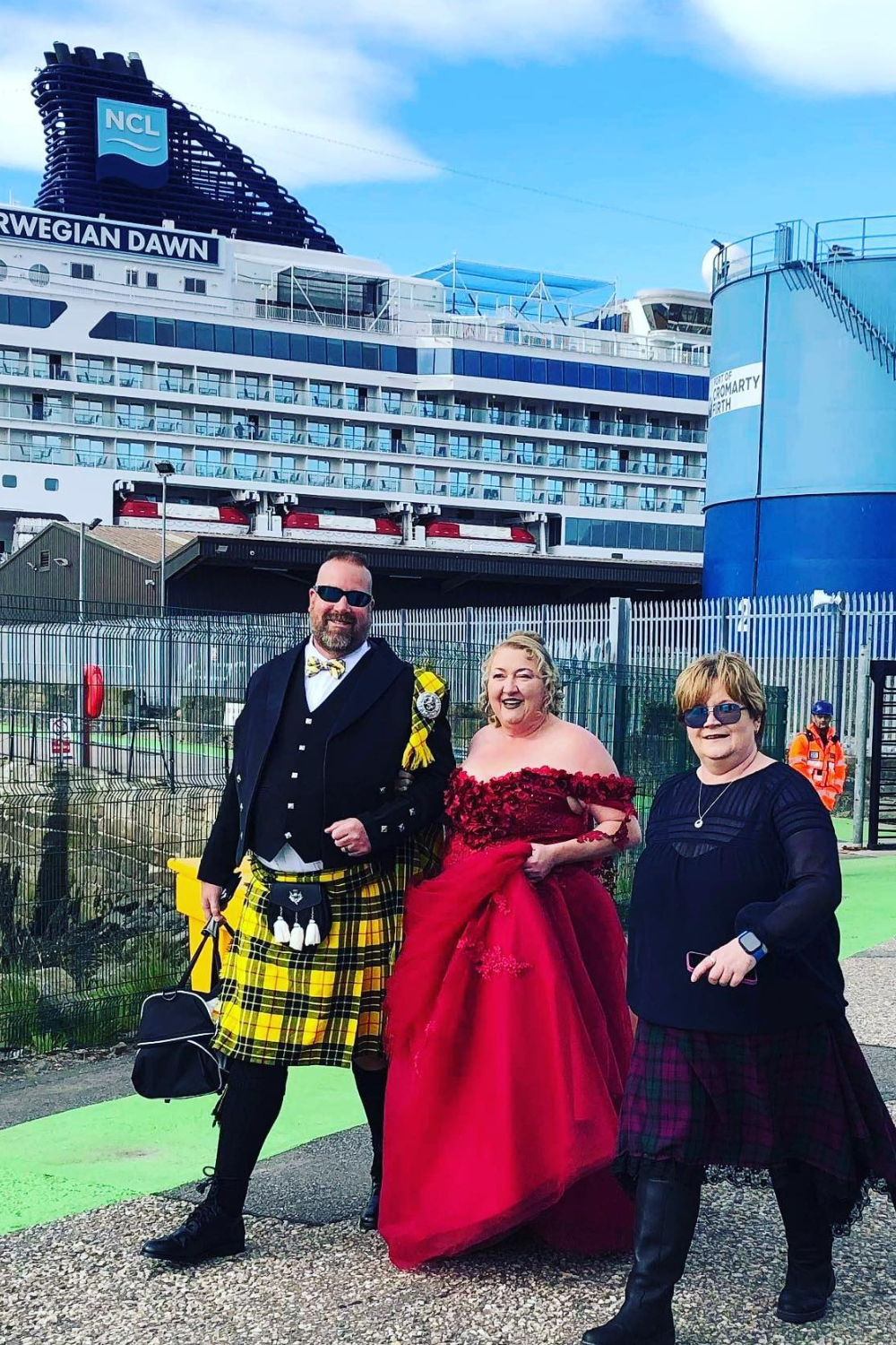 A man in a kilt is standing next to a woman in a red dress.