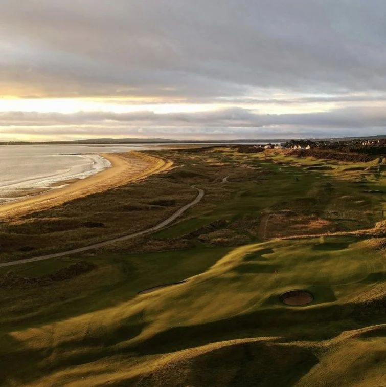 An aerial view of a golf course with a beach in the background.